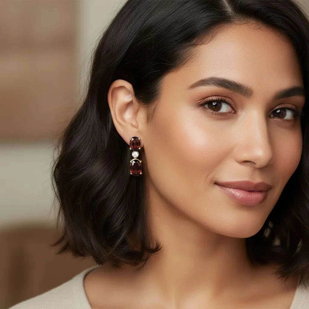 Close-up of a woman wearing women's 18K yellow gold plated sterling silver earrings with red garnets and round-cut diamonds