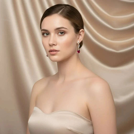 Elegant women's 14K yellow gold teardrop earrings with pear-cut rubies and round diamonds on model