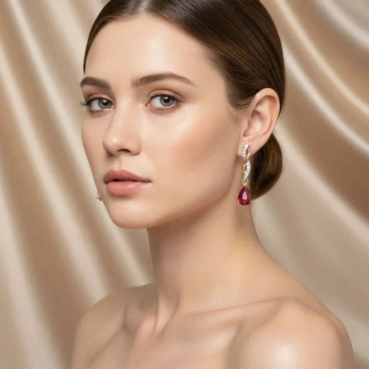 Woman wearing elegant 14K yellow gold teardrop earrings with pear-cut ruby and diamond accents
