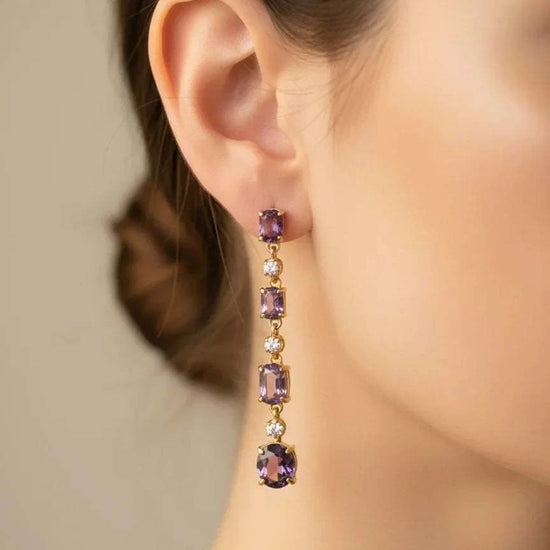 Close-up of a woman's ear wearing 18K yellow gold over sterling silver free fall earrings with amethyst and diamond gemstones
