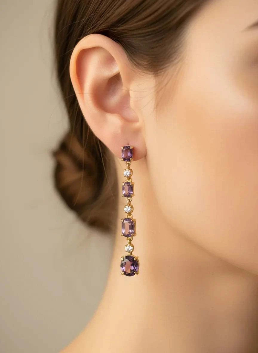 Close-up of a woman's ear wearing 18K yellow gold over sterling silver free fall earrings with amethyst and diamond gemstones