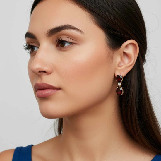 Woman wearing women’s 18K yellow gold earrings with red garnets and diamonds